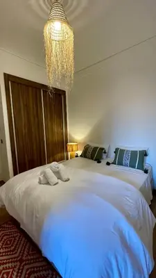 a bedroom with a large white bed with a chandelier at Cozy apartment with pool Downtown Marrakech in Marrakech