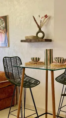 a glass table with two chairs and a vase on a wall at Cozy apartment with pool Downtown Marrakech in Marrakech