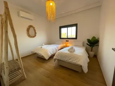 a bedroom with two beds and a window and a chandelier at Cozy apartment with pool Downtown Marrakech in Marrakech