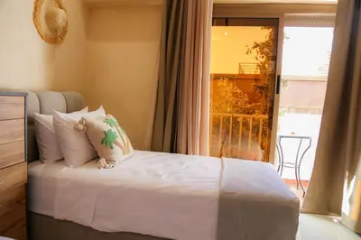 a bedroom with a bed with white sheets and a window at Stylish YSL Street 2-BDR, parking, hi speed wifi in Marrakech