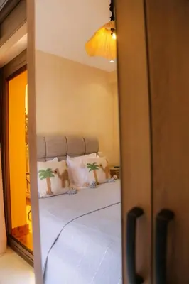 a bedroom with a bed with two pillows and a mirror at Stylish YSL Street 2-BDR, parking, hi speed wifi in Marrakech