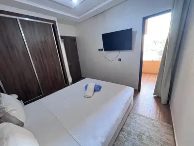 a bedroom with a white bed and a flat screen tv at Appartement chic & elegant in Marrakech
