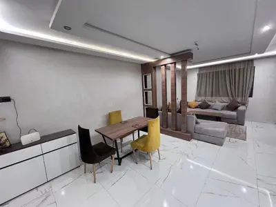 a living room with a wooden table and yellow chairs at Appartement chic & elegant in Marrakech
