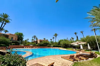 a pool at a resort with chairs and palm trees at Sunny apartment in Palmeraie with Pools and Gardens in Marrakech