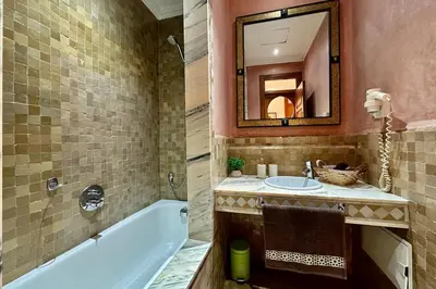 a bathroom with a tub and a sink and a mirror at Sunny apartment in Palmeraie with Pools and Gardens in Marrakech