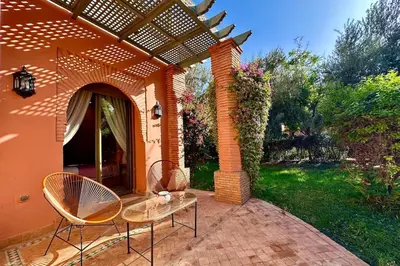 a patio with two chairs and a table in front of a house at Sunny apartment in Palmeraie with Pools and Gardens in Marrakech