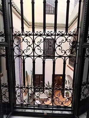 an open wrought iron door with a view of a balcony at Riad Awel Oasis Privée au coeur de la Medina in Marrakech
