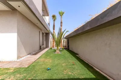 a yard between two buildings with palm trees at Villa NAYA in Marrakech