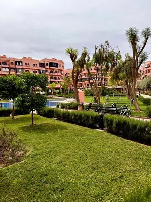 a park with benches and trees and a building at Marrakech Luxury Apartment with Pool & gym in Marrakech