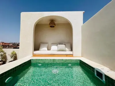 a house with a swimming pool and a bed on a patio at Riad Hami in Marrakech