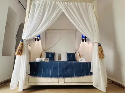 a bedroom with a canopy bed with white curtains at Riad Hami in Marrakech