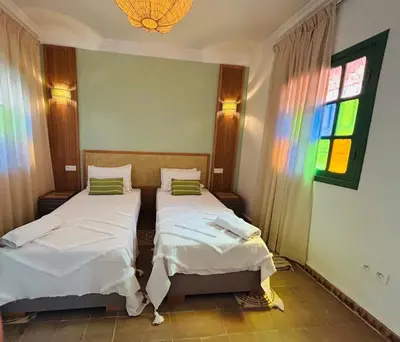 two beds in a room with a stained glass window at Riad Hami in Marrakech