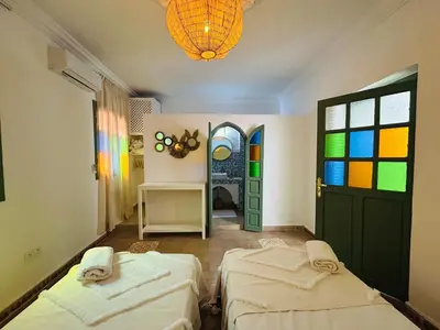 a room with two beds and a rainbow window at Riad Hami in Marrakech