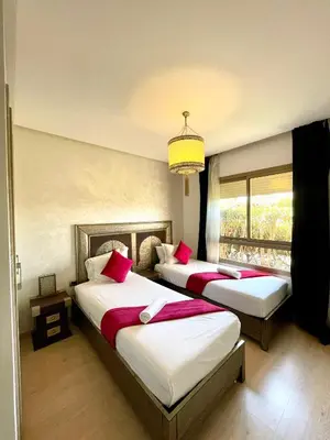 a bedroom with two beds with red pillows at Prestigia jade in Marrakech