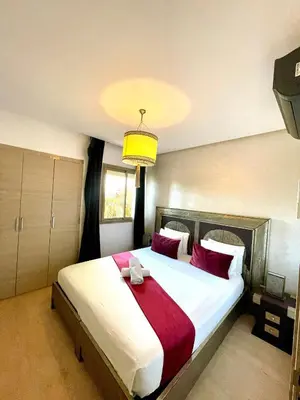 a bedroom with a large bed with red pillows at Prestigia jade in Marrakech