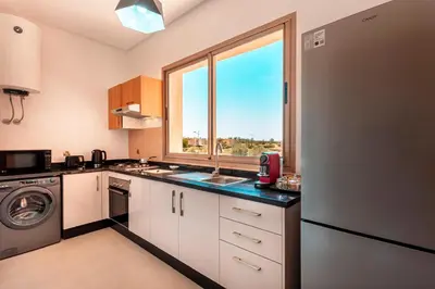 a kitchen with a refrigerator and a sink and a window at Appartement de charme vue piscine et espace vert in Marrakech