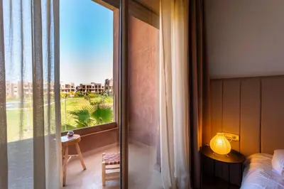 a bedroom with a bed and a window with a view at Appartement de charme vue piscine et espace vert in Marrakech