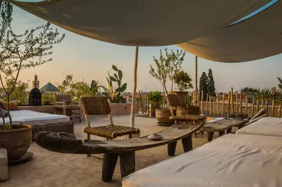 a patio with beds and chairs and an umbrella at Riad 144 in Marrakech