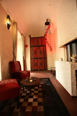 a living room with a fireplace and a red door at Riad 144 in Marrakech