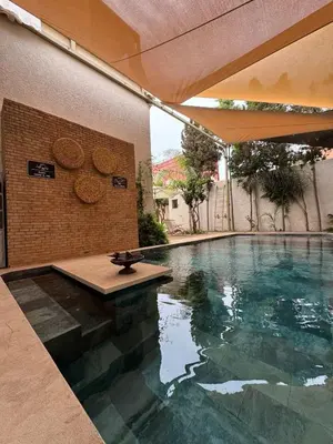a swimming pool with a table on the side of a building at Villa en centre Ville de Marrakech, 5 Chambres, Piscine, Rooftop in Marrakech
