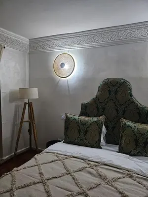 a bedroom with a bed with a headboard and a lamp at Riad Dar Lghizlane in Marrakech