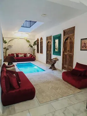 a living room with a pool and red furniture at Riad Dar Lghizlane in Marrakech