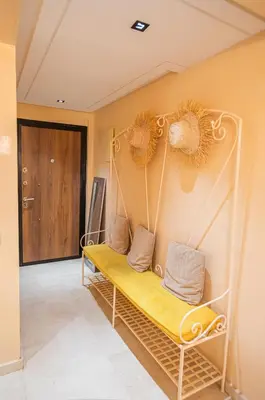 a yellow bench in a room with a door at Appartement XXL résidence privée piscine Dar Dmana PALMERAIE in Marrakech