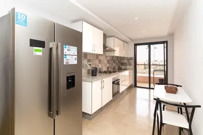 a kitchen with a stainless steel refrigerator and a table at Beautiful accommodation with 2 pools & fast WiFi in Marrakech