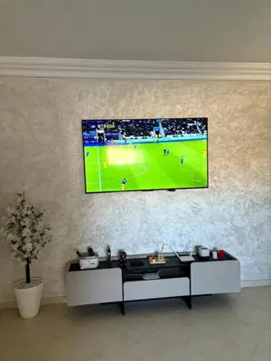 a television hanging on a wall in a living room at Joyau Moderne Appartement in Marrakech