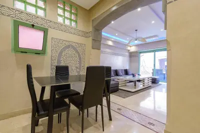 a dining room with a table and chairs and a couch at Appartement Confort - Hivernage - Piscine in Marrakech