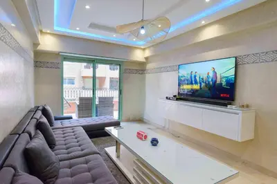 a living room with a couch and a flat screen tv at Appartement Confort - Hivernage - Piscine in Marrakech