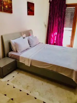 a large bed in a bedroom with a red window at Appartement Ihssane Plaza Kech in Marrakech