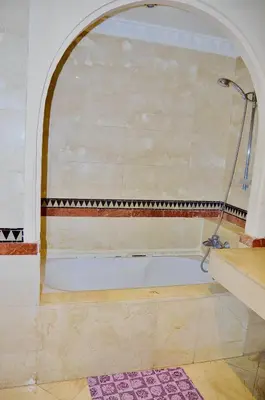 a bath tub in a bathroom with an archway at Appartement Ihssane Plaza Kech in Marrakech