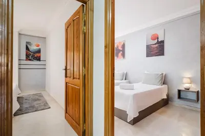 a white bedroom with a bed and a door at apartment gilez in Marrakech