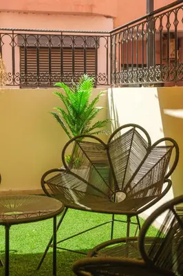 a chair and two tables and a plant on a balcony at apartment gilez in Marrakech