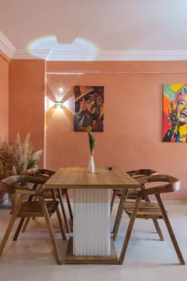 a table and chairs in a room with paintings at apartment gilez in Marrakech
