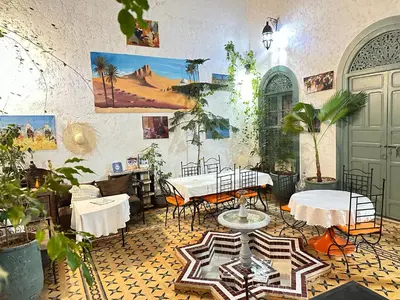 a room with tables and chairs and paintings on the wall at Dar JOMANA in Marrakech
