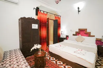 a bedroom with two beds and a table with flowers at Dar JOMANA in Marrakech
