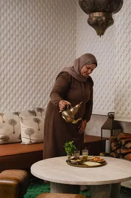 a woman standing next to a table with a plate of food at Riad Mint - Luxury Oasis in the Medina with Pool in Marrakech