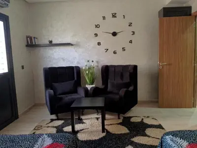 a living room with two chairs and a clock on the wall at Appartement meublé à louer à Marrakech in Marrakech