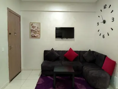 a living room with a couch and a clock on the wall at Appartement meublé à louer à Marrakech in Marrakech