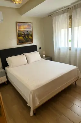 a bedroom with a large white bed with a painting on the wall at Appartement familial moderne et cosy in Marrakech