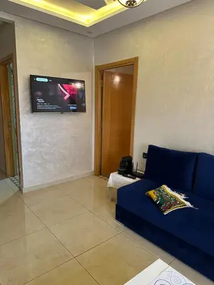 a living room with a blue couch and a flat screen tv at Appartement familial moderne et cosy in Marrakech