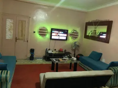 a living room with a blue couch and a tv at ÉTABLISSEMeNT BEAU SÉJOUR in Marrakech