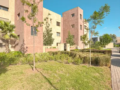 a large brick building with trees in a yard at Cocon Prestigia Argan avec piscine & parking in Marrakech