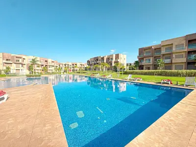 a large blue swimming pool in a building at Cocon Prestigia Argan avec piscine & parking in Marrakech