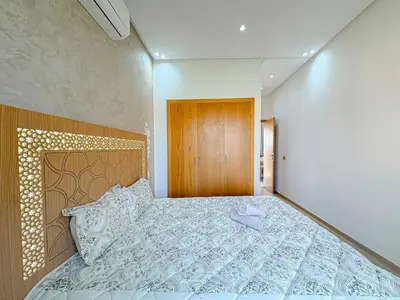a bedroom with a large bed and a wooden door at Cocon Prestigia Argan avec piscine & parking in Marrakech