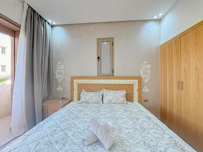 a bedroom with a large bed and a mirror at Cocon Prestigia Argan avec piscine & parking in Marrakech