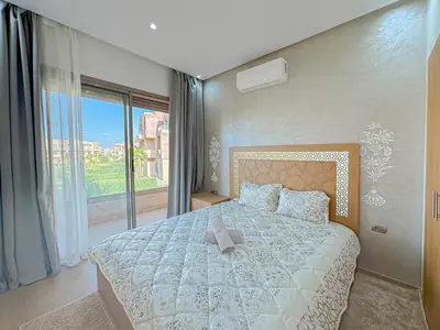 a bedroom with a large bed and a large window at Cocon Prestigia Argan avec piscine & parking in Marrakech