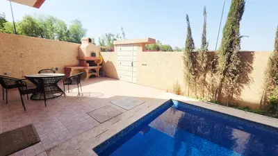 a patio with a table and chairs next to a pool at Villa with private pool in Marrakech